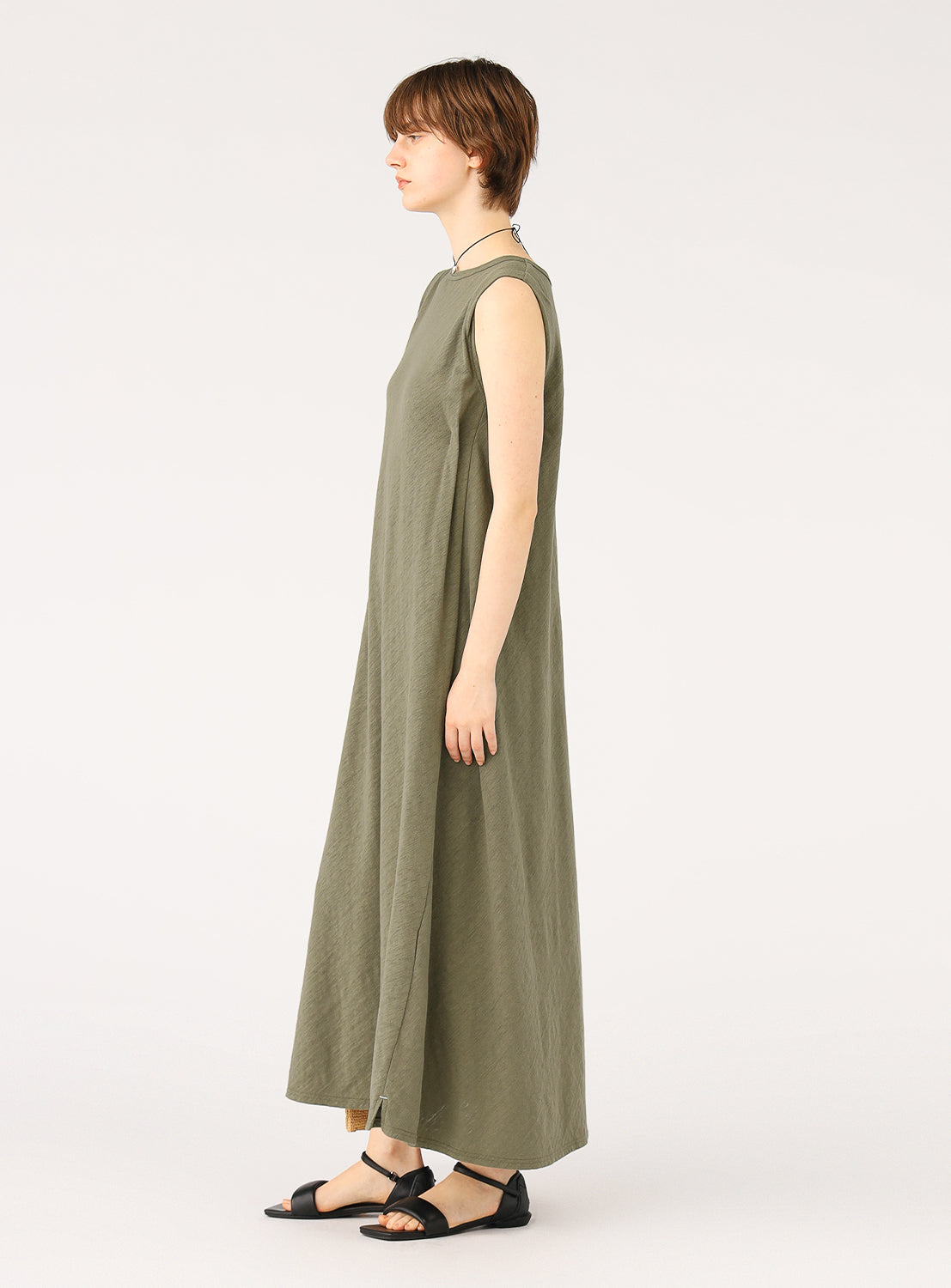 Side view of a model wearing an olive green maxi dress, showing the relaxed drape and flowy silhouette.