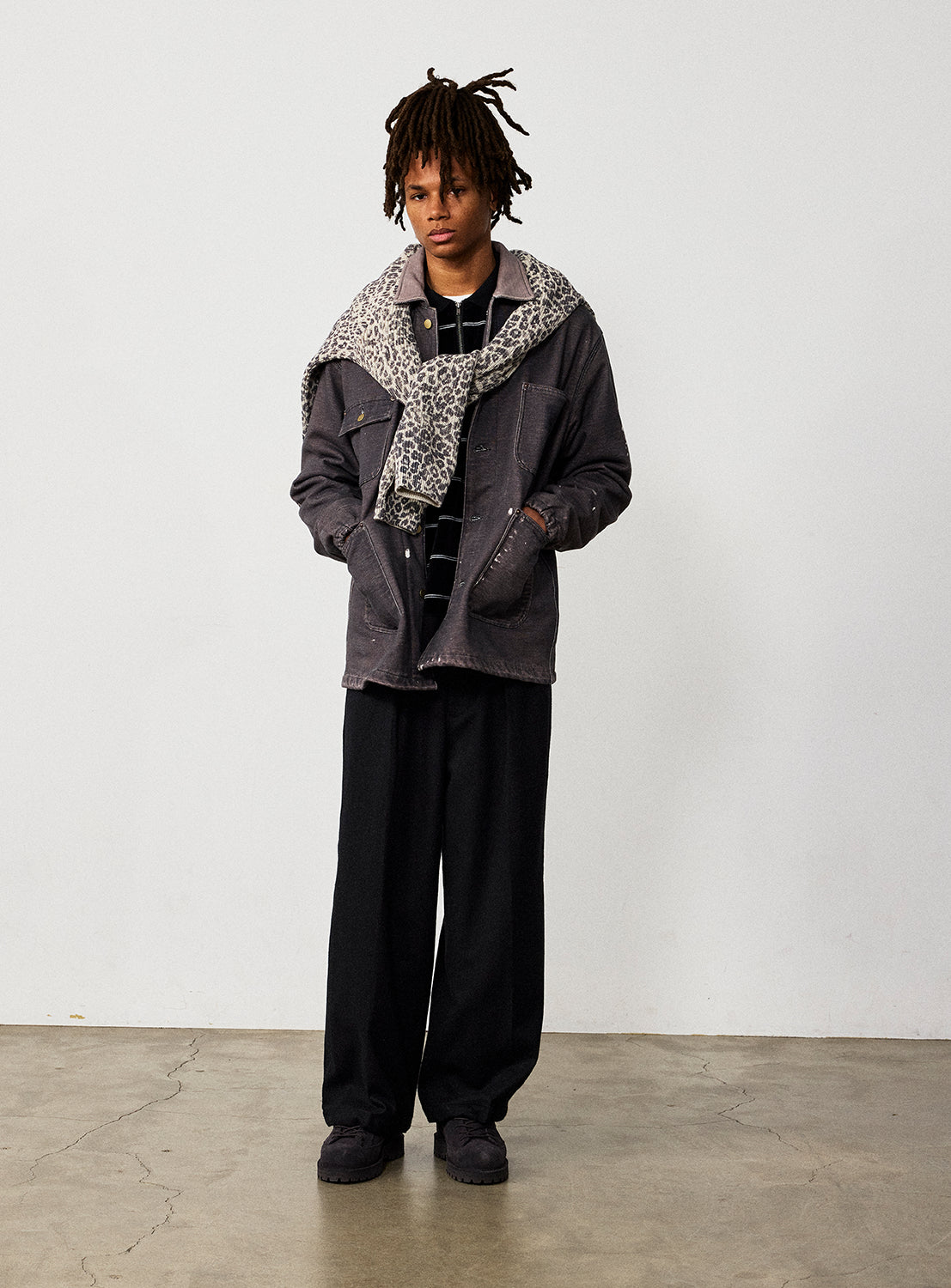 A person wearing a relaxed fit BEAMS Used Denim Coverall with a leopard-print sweater draped over their shoulders, a striped shirt, and wide-leg trousers.