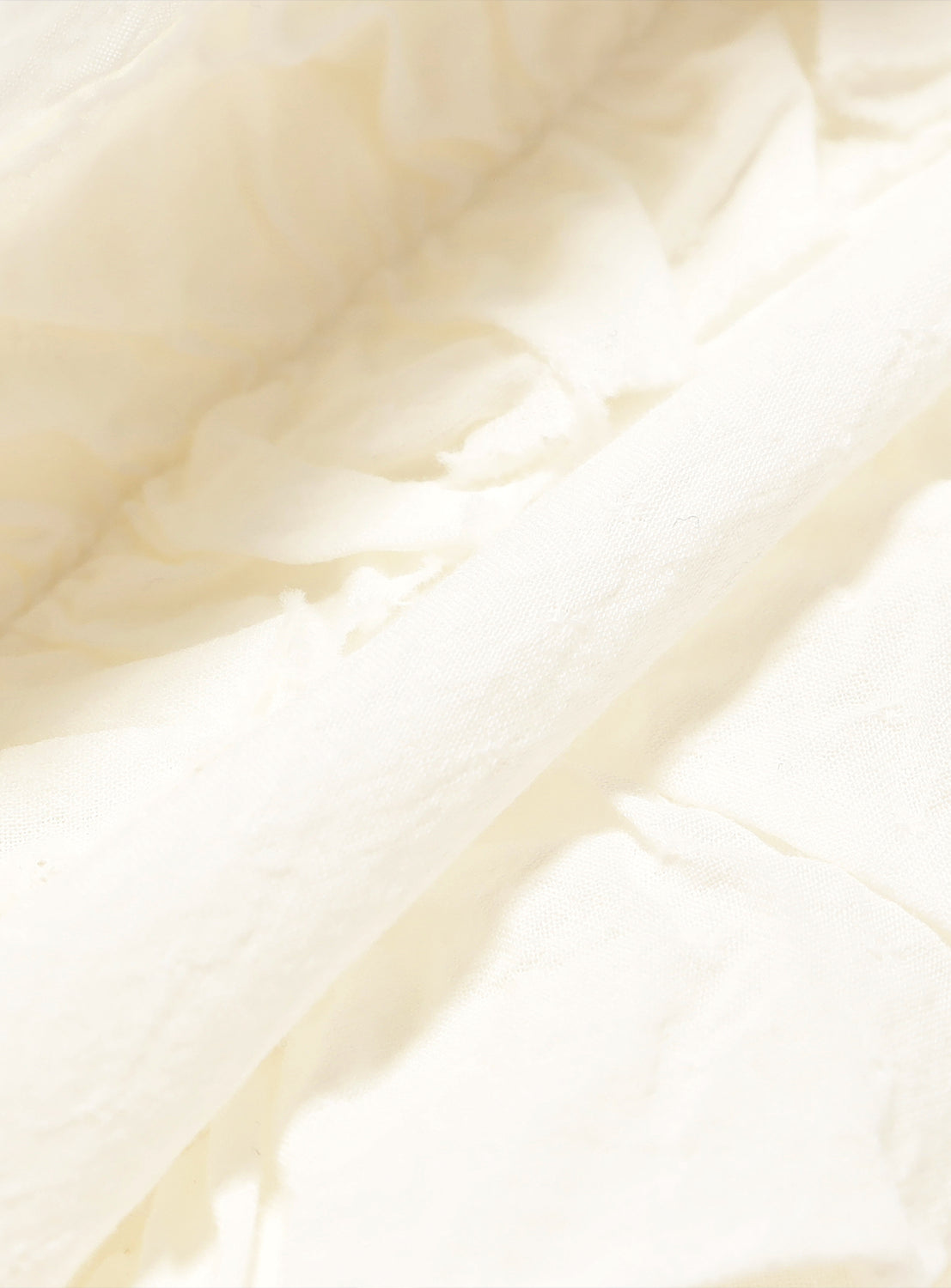 White fabric, revealing a detailed crinkle and ruffle texture.
