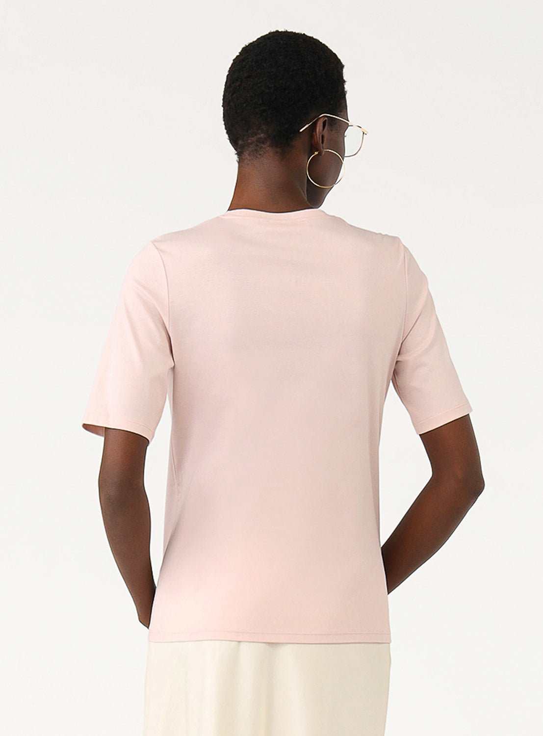Back view of a model in the pink cotton t-shirt, highlighting the neckline and fit.