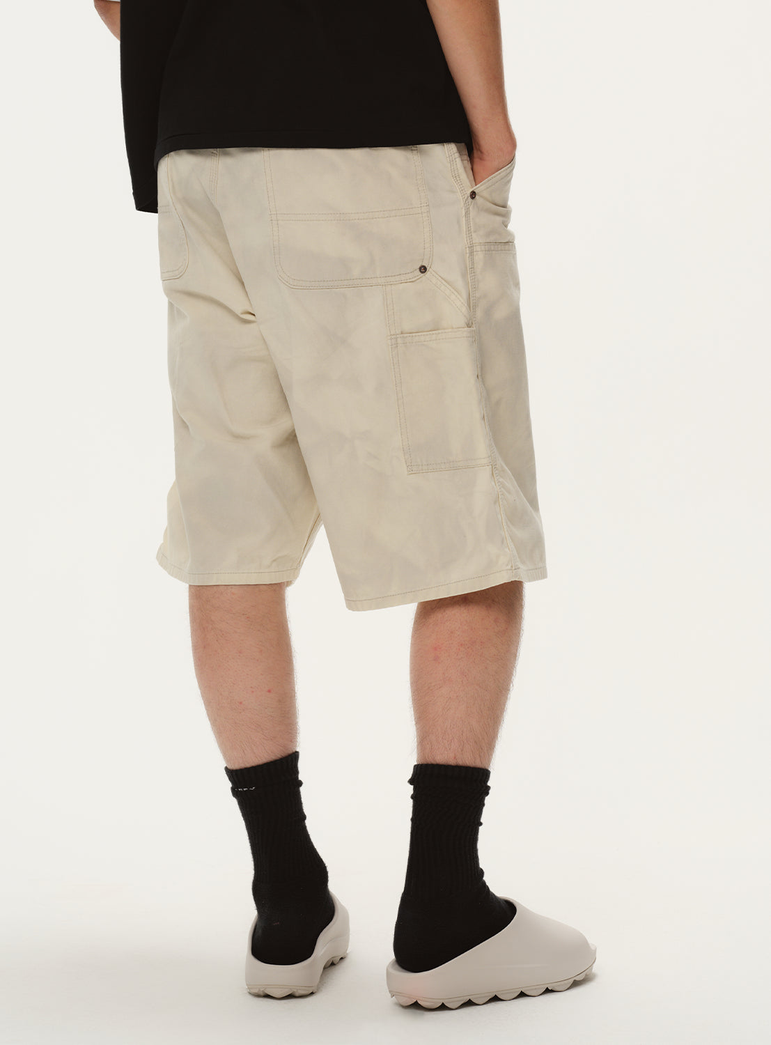 Back view of a model in the ivory shorts, highlighting the tailored fit and back pocket detail.