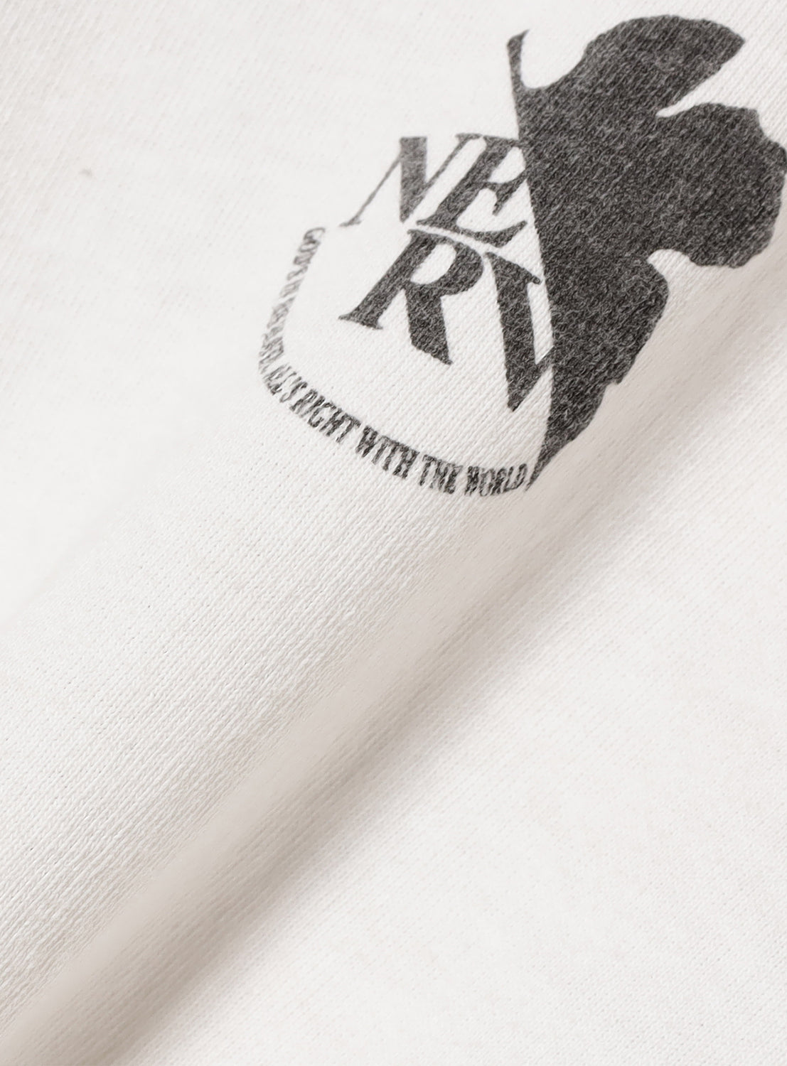 Close-up of the NERV logo on the t-shirt, highlighting the vintage-worn look and distressed finish.