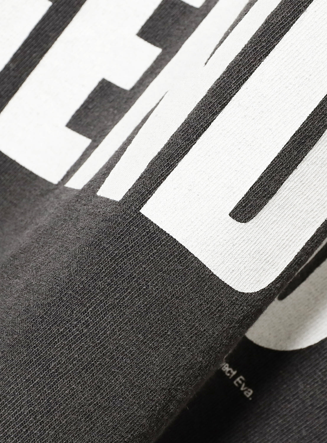 Close-up of the grey tee fabric, highlighting the bold white text and distressed, vintage finish.