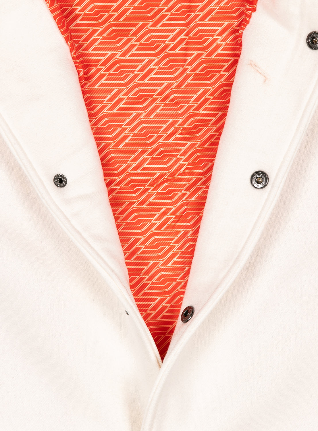 Close-up of a white jacket with a red lining with F1 logo pattern. 