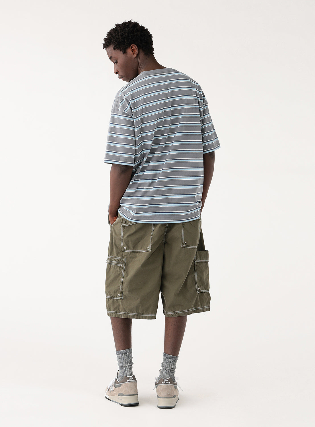Back view of a model in the olive green shorts, highlighting the back pockets and contrast stitching.