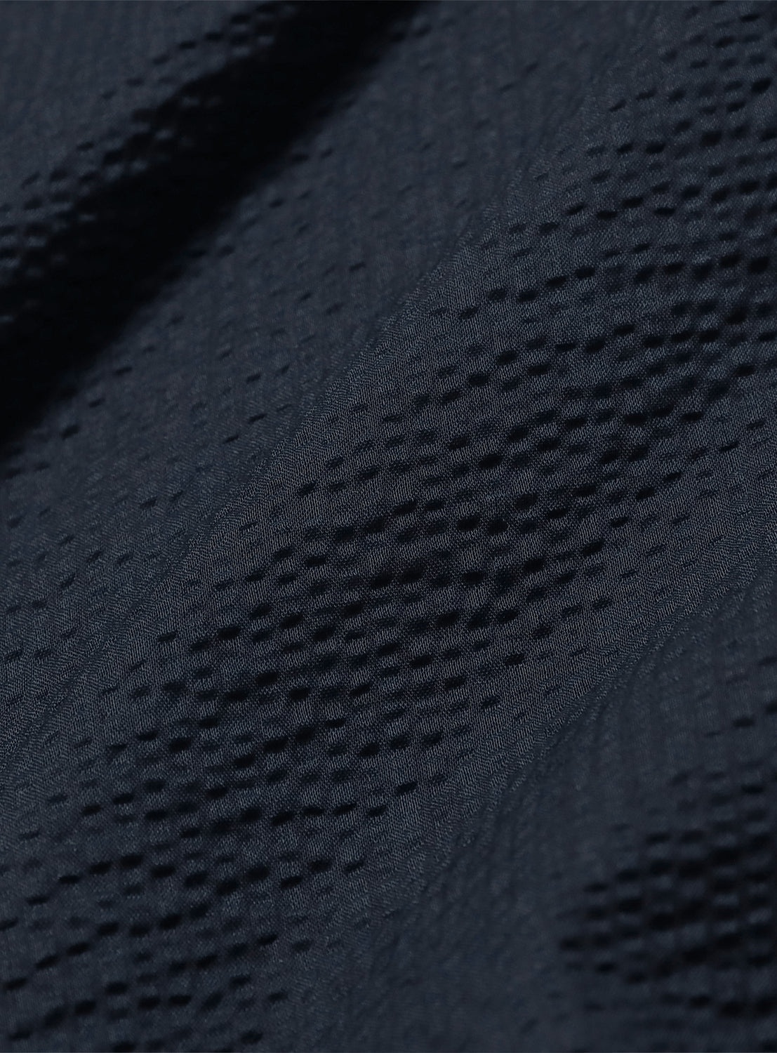 Close-up of the textured navy blue fabric of the dress, showing subtle folds.