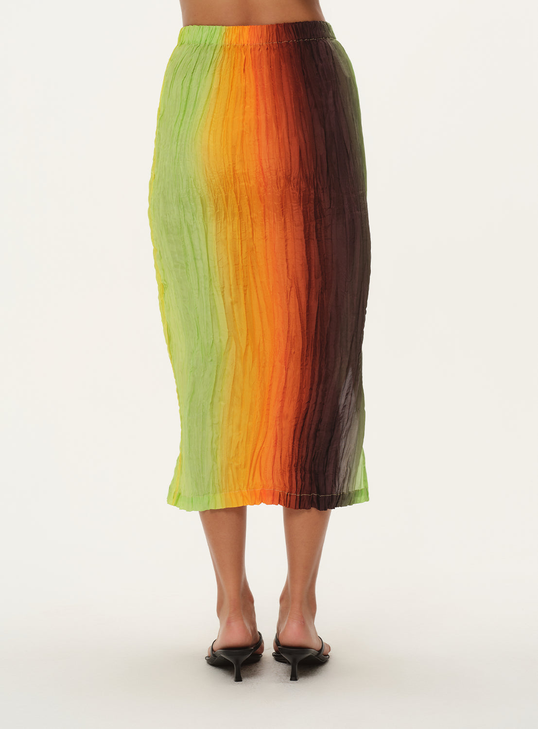 A partial-view of a woman from the waist down, wearing a vertically striped knit midi skirt, showcasing the hem.