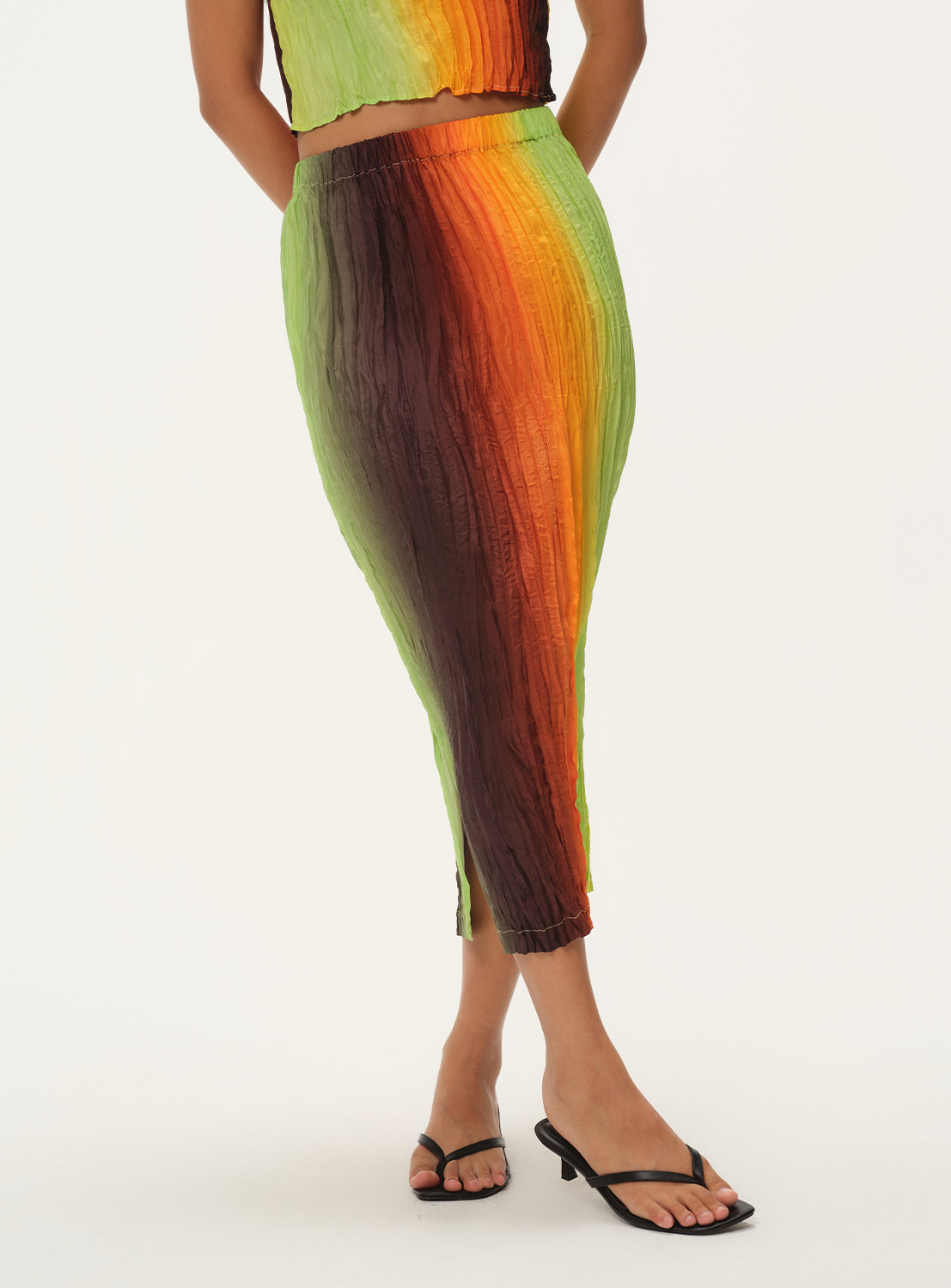 A cropped, profile view of a woman wearing a vertically striped knit midi skirt, highlighting the waist and hip silhouette.