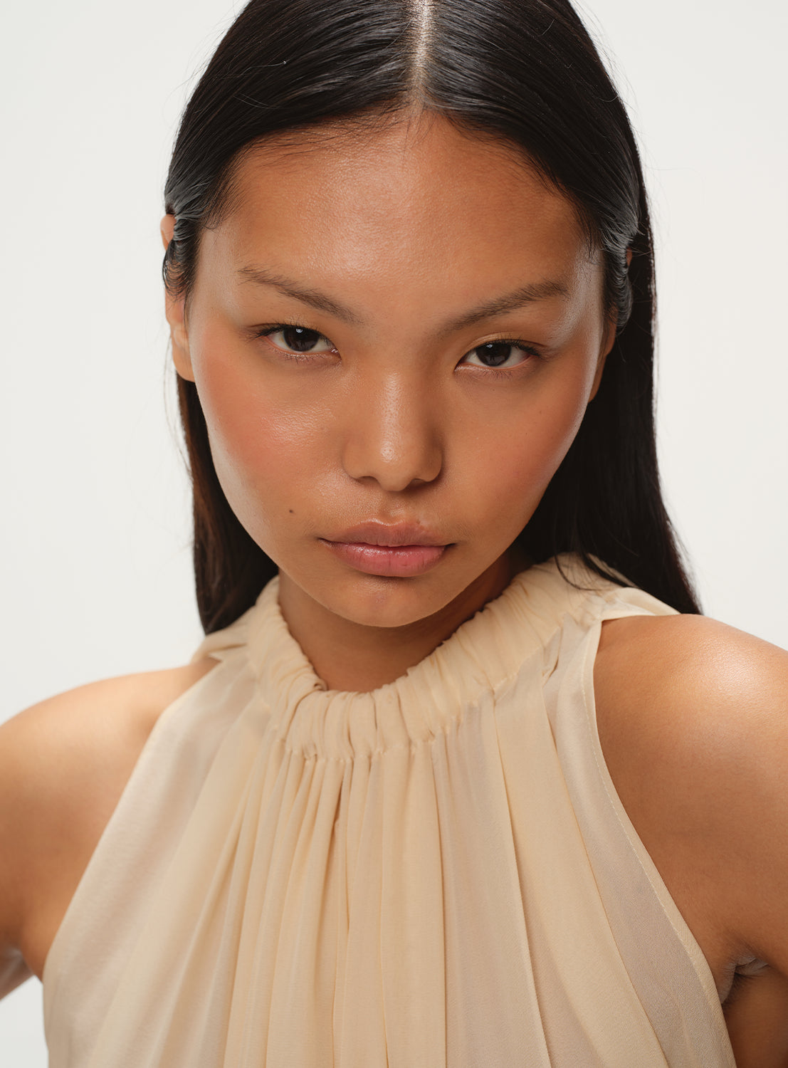 Close up of a beige flowy silk dress with a high neck. 