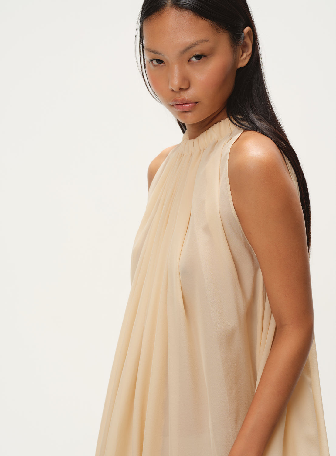 Close up of beige flowy silk dress with a high neck.