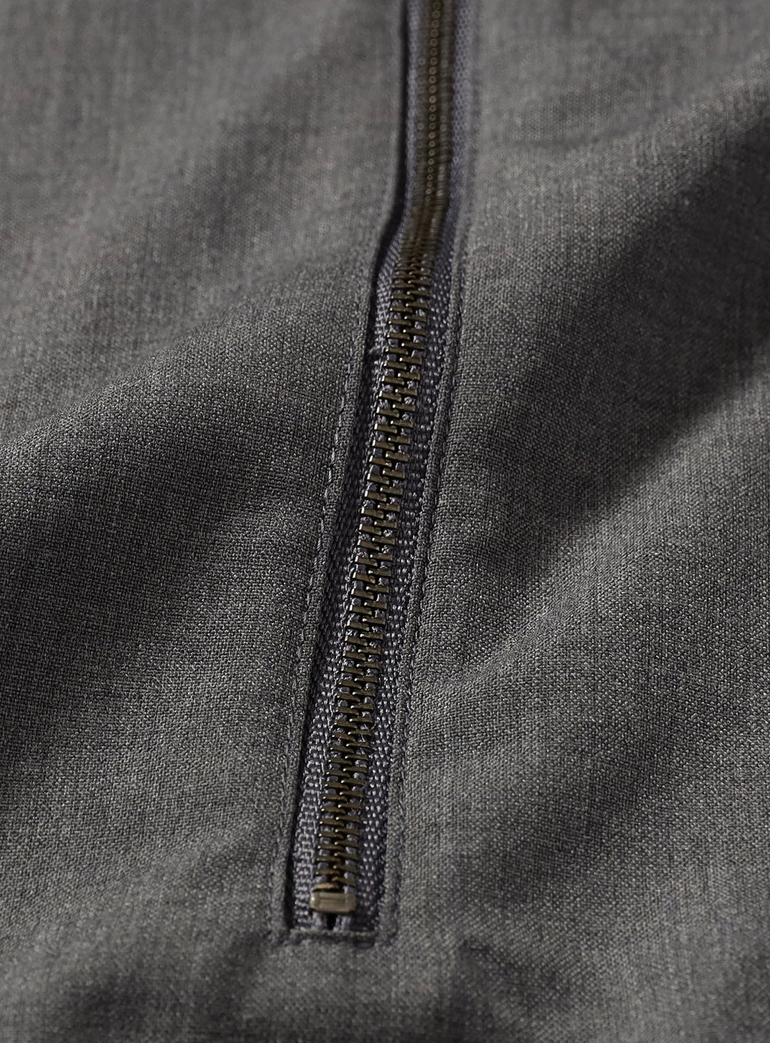 Close-up of a silver zipper on the grey pullover shirt. 