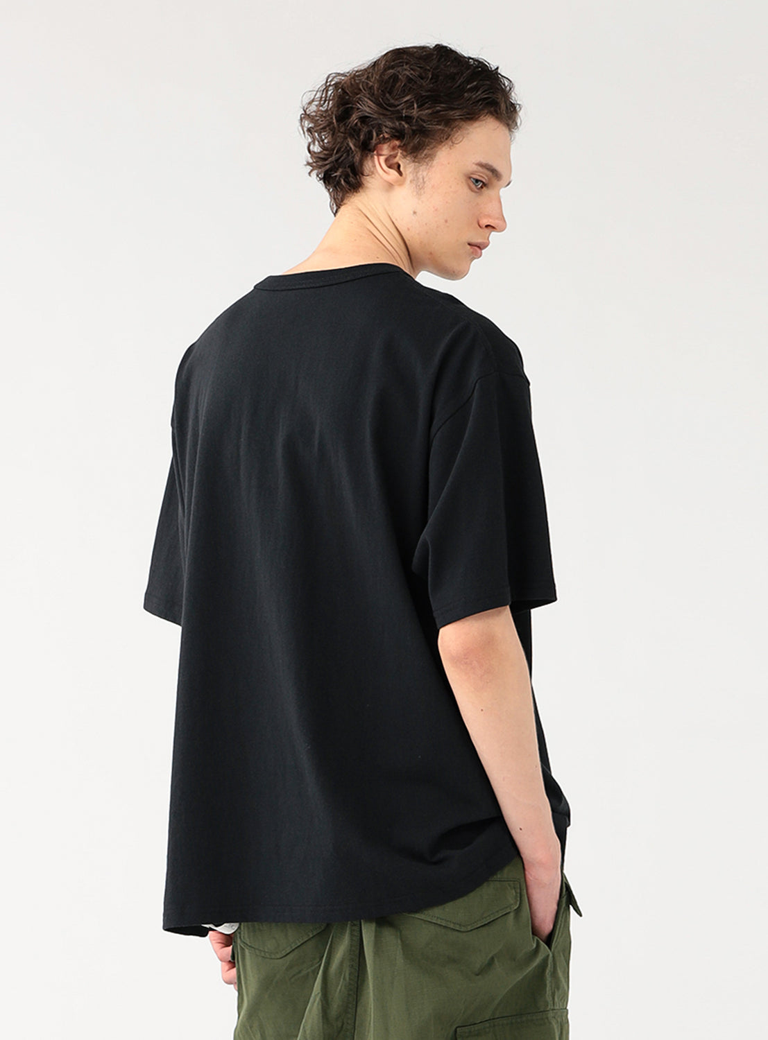 Back view of a man showcasing the fit of a black oversized t-shirt demonstrating drape.