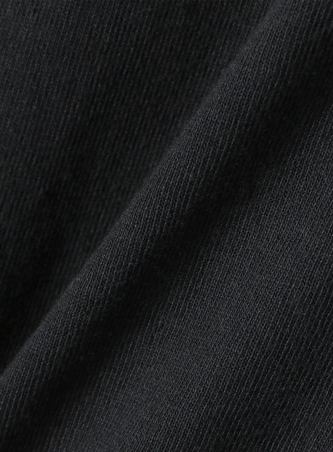 Extreme close-up of the deep black cotton fabric, revealing its soft texture and quality.