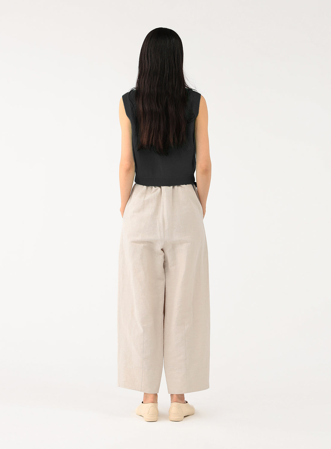 Back view of a model in the oyster beige cropped pants, highlighting the relaxed fit and high waist.