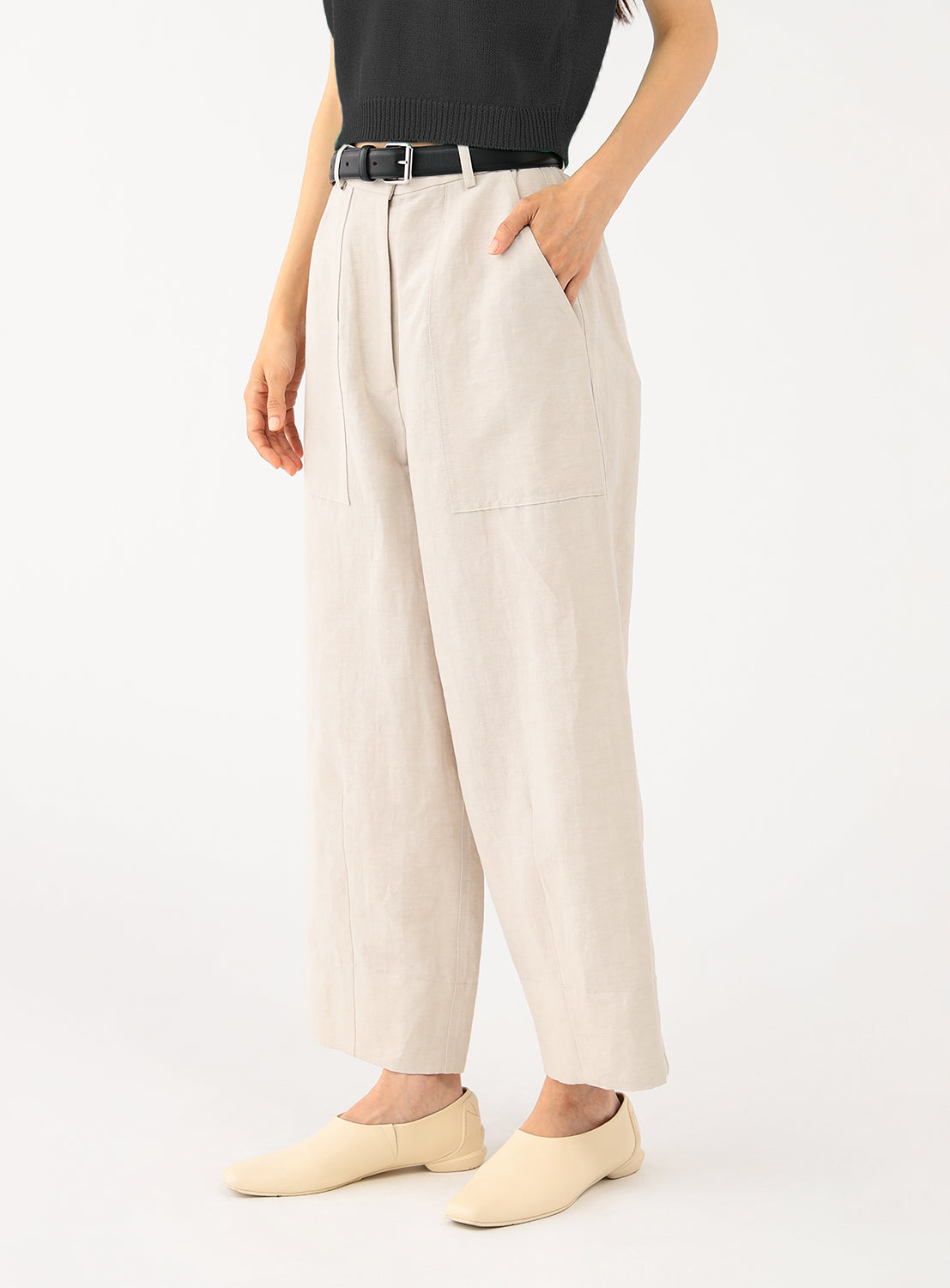 Close-up of a model wearing the high-waisted pants, with a focus on the pleats and fabric texture.