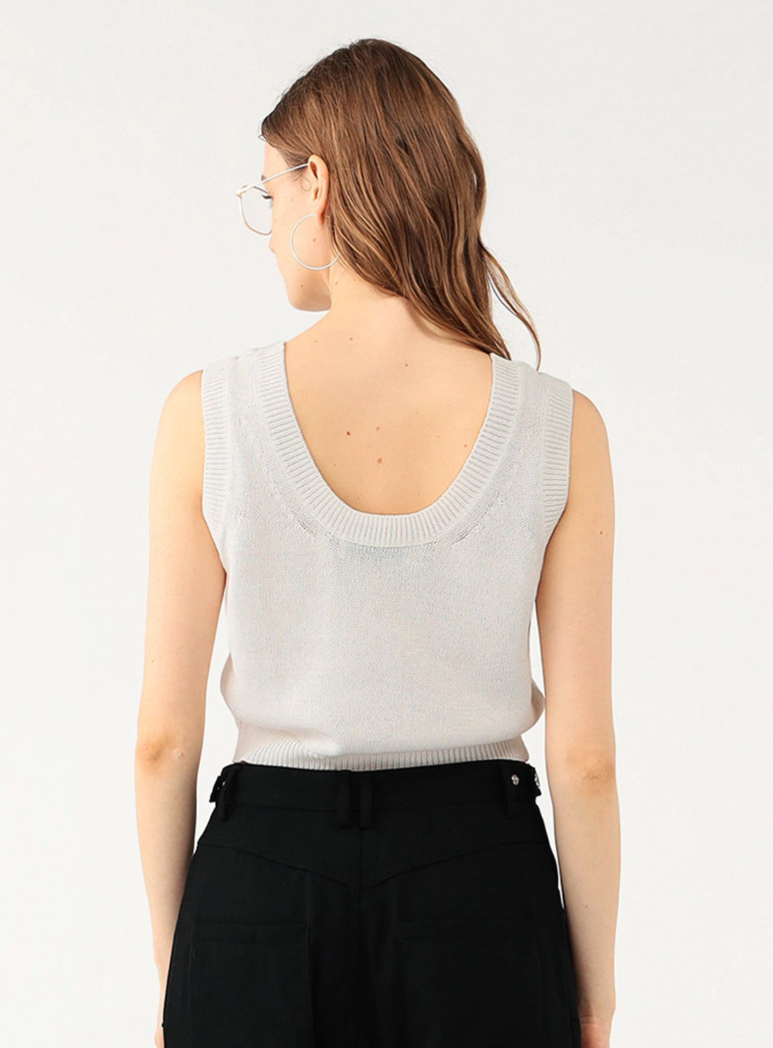 Back view of a model in the white knit top, highlighting the scoop back and ribbed detail.