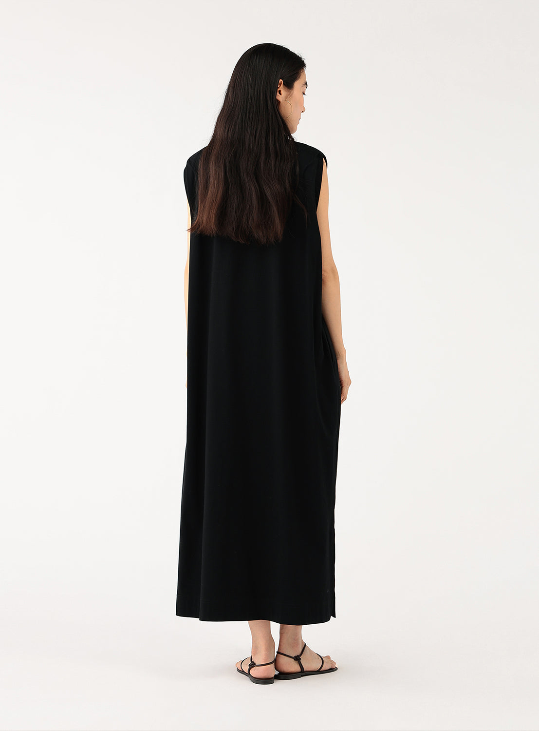 Back view of a model wearing a black midi dress, showing the simple crew neck and comfortable fit.