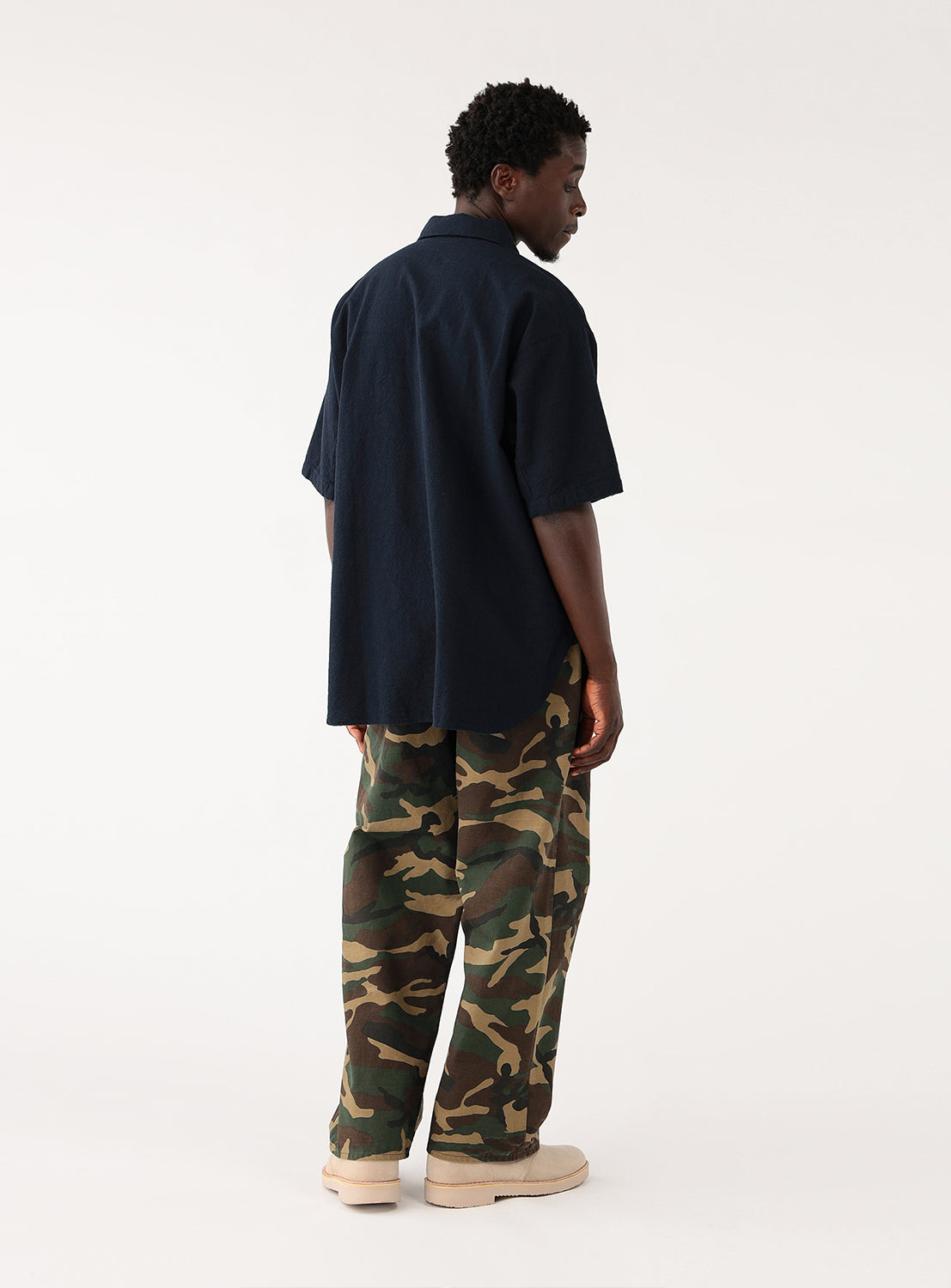Model wearing navy blue open-collar shirt and camouflage pants, full back view, ideal for layering.