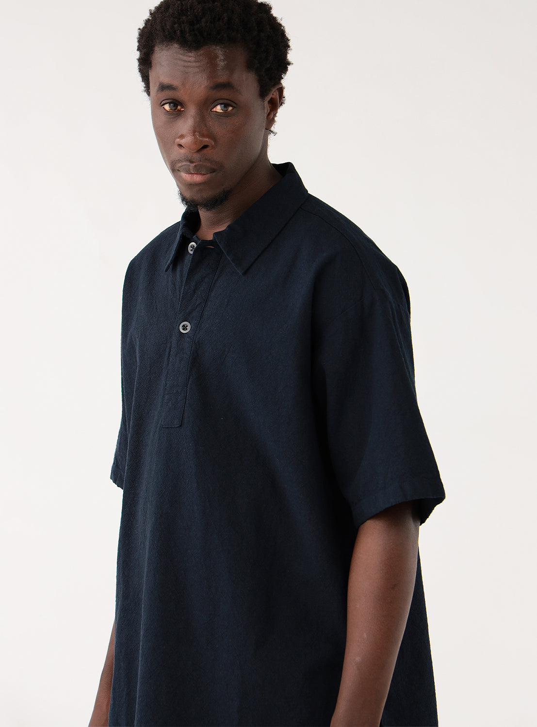 Model wearing navy blue open-collar shirt and camouflage pants, side profile, highlighting the elasticated cuffs.
