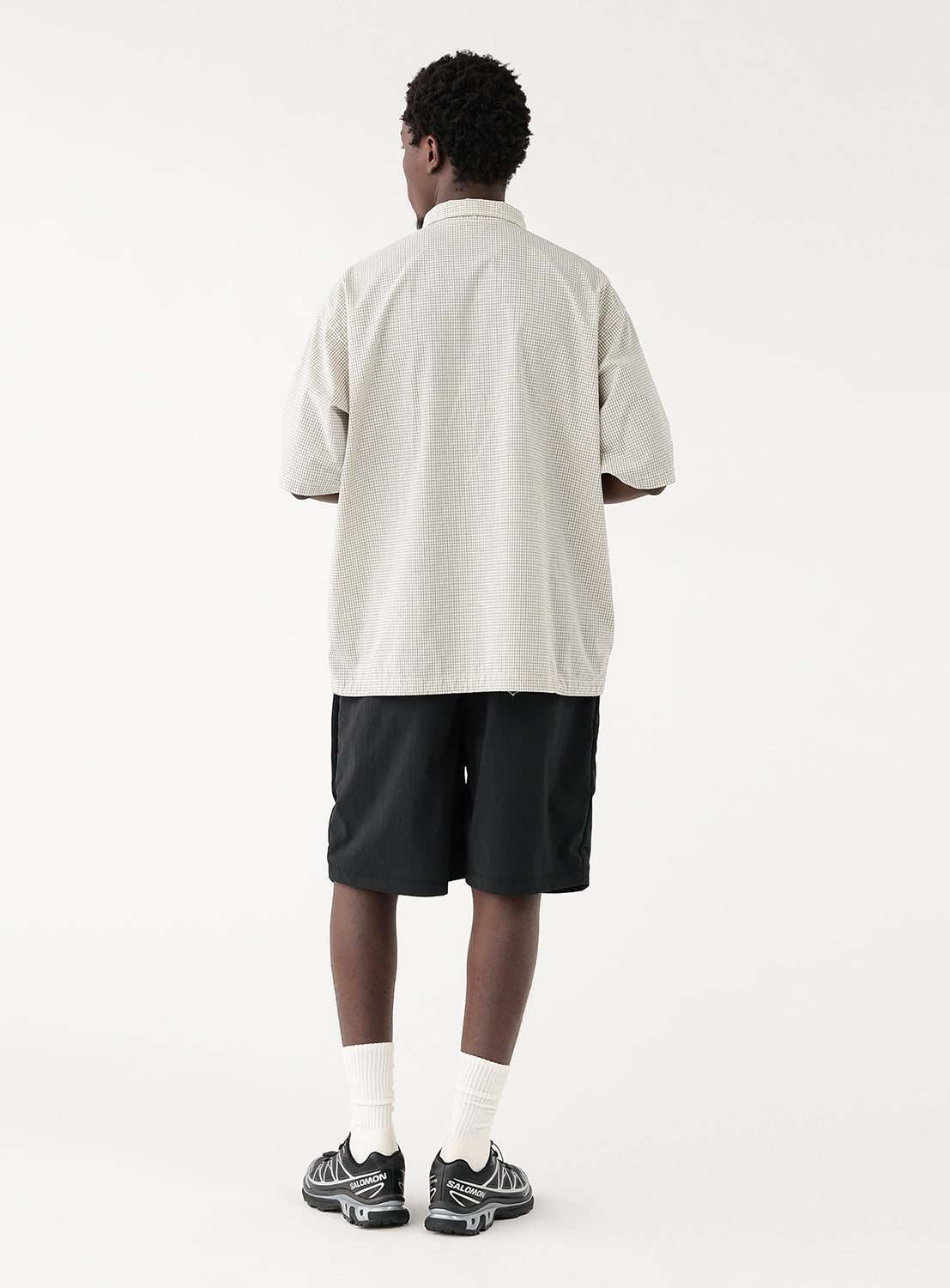 Model wearing an off-white check-patterned pullover shirt, back view, showcasing its effortless drape and clean finish.
