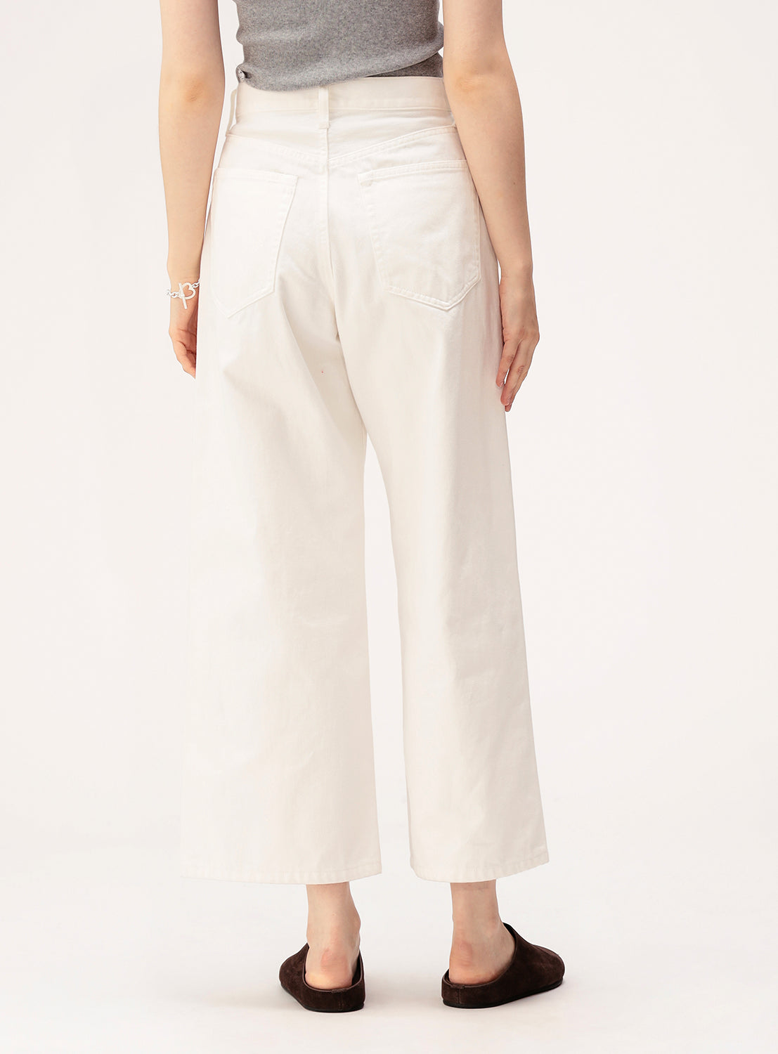 A person, seen from behind, wears BEAMS BOY Straight Fit Wide Denim Pants with a classic 5-pocket design, paired with a gray sleeveless top, black slip-on shoes, and a bracelet on their left wrist.