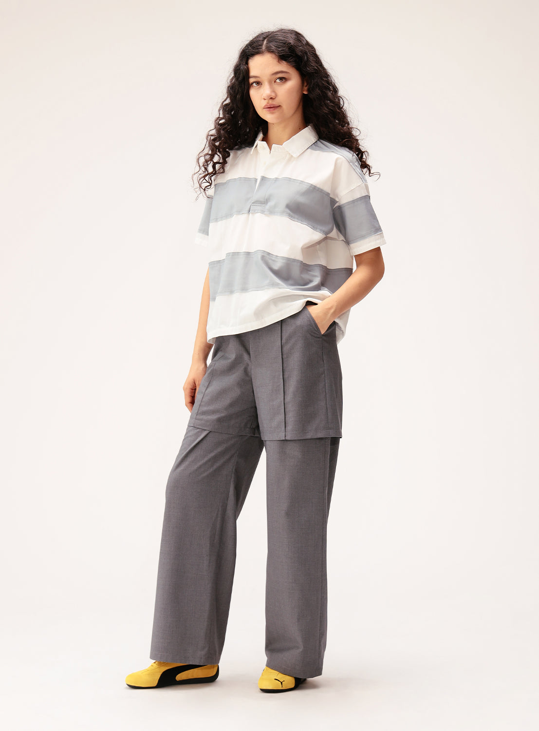 Person wearing a striped shirt and gray pants on a white background