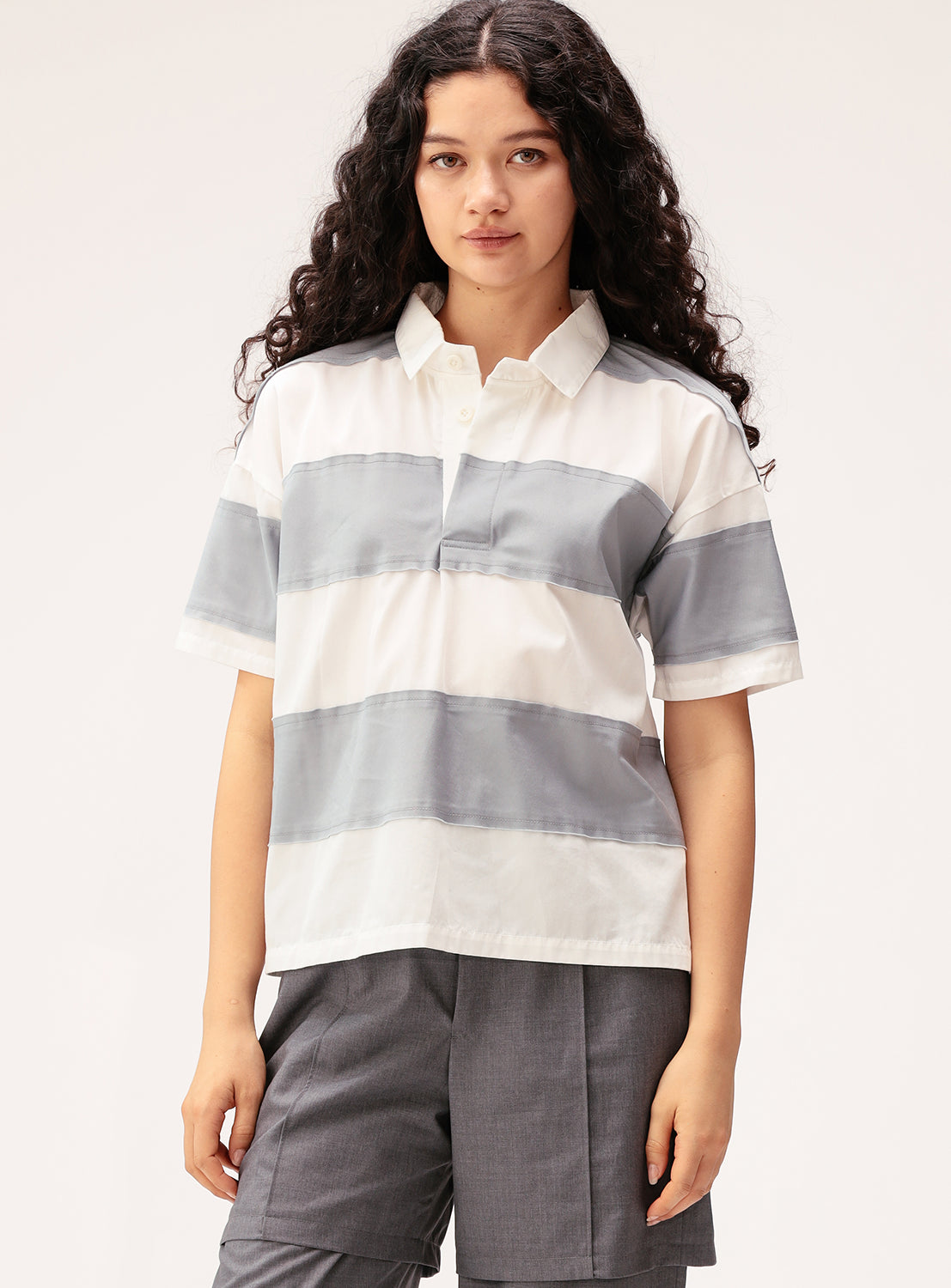Person wearing a white and gray striped shirt with gray pants on a white background