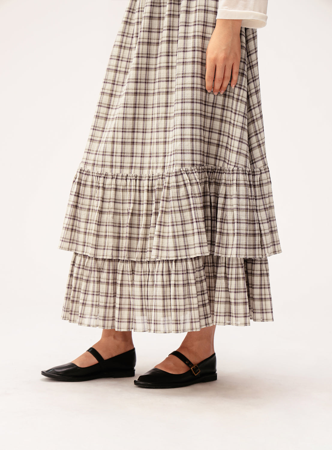 A person stands against a plain background, wearing the BEAMS BOY Check Tiered Skirt paired with black Mary Jane shoes. Only the lower half of the body is visible.