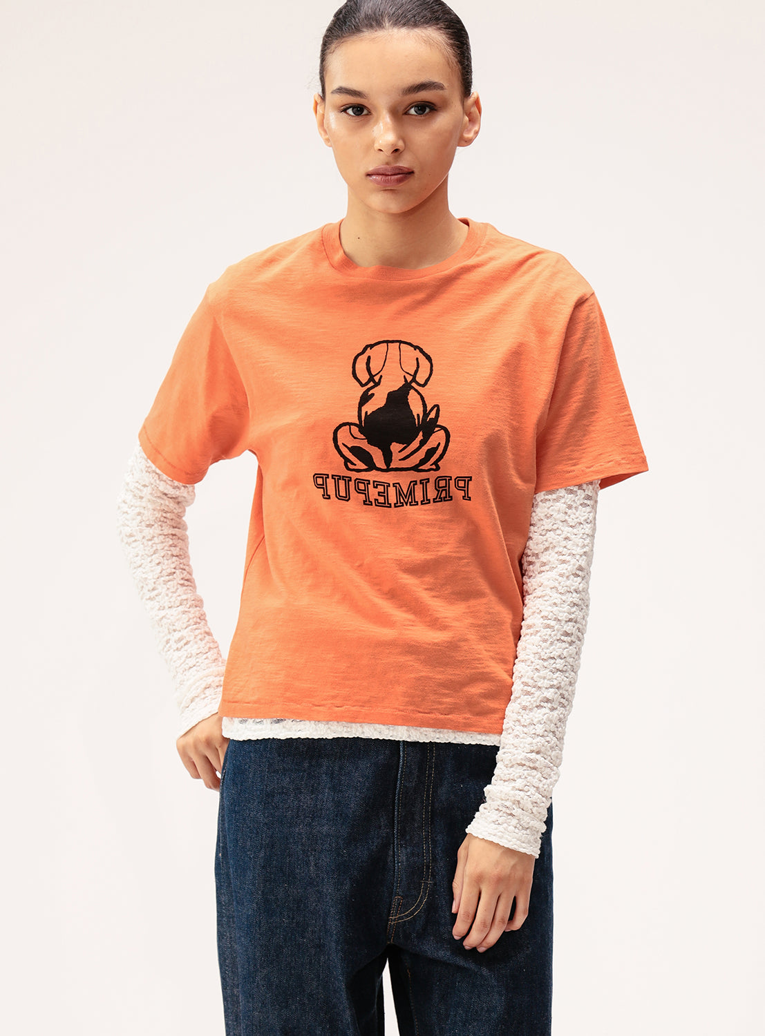 Person wearing an orange t-shirt with a graphic design on a plain background