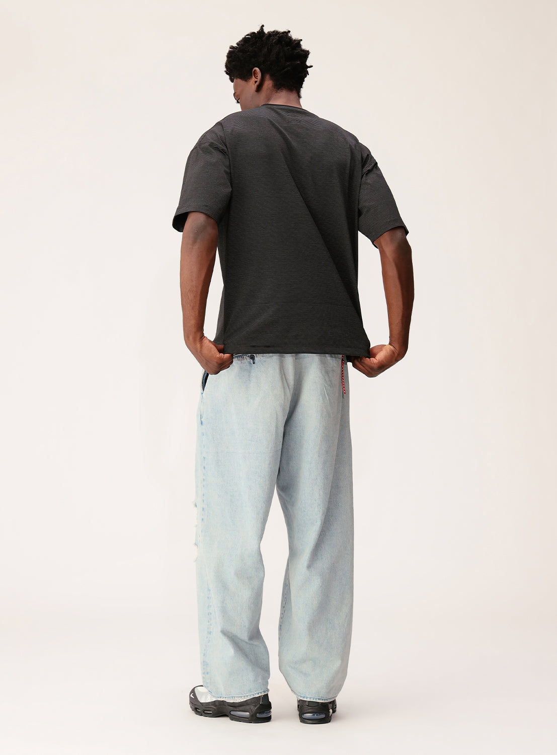 Person wearing a dark gray t-shirt and light blue jeans on a white background