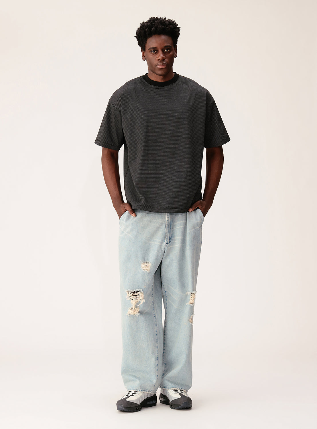 Person wearing a black t-shirt and light blue jeans on a white background