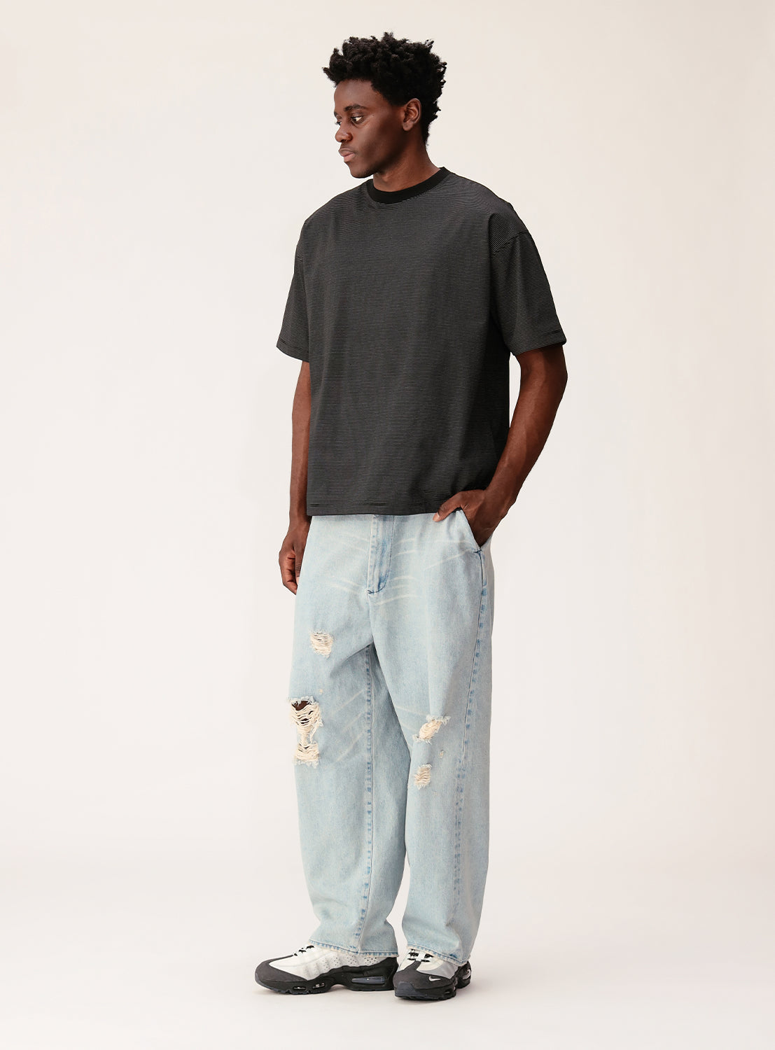 Person wearing a black t-shirt and light blue jeans on a white background