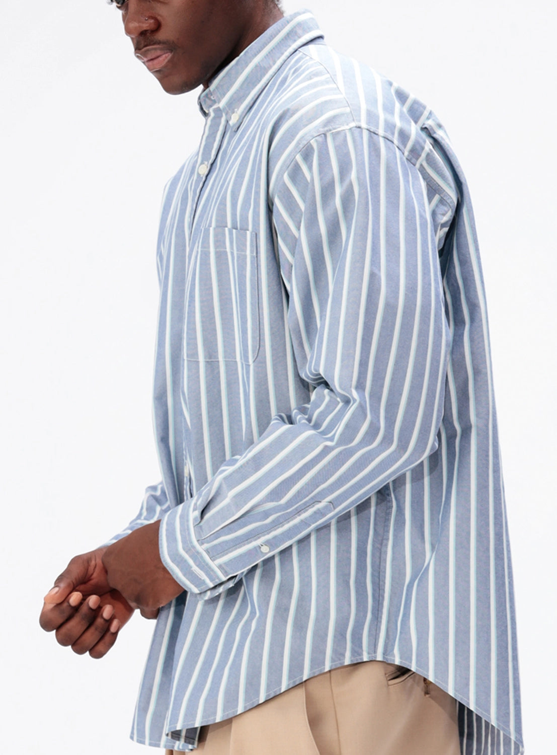 A person wearing a BEAMS Heavy Oxford Button-Down Shirt in blue and white stripes with an oversized chest pocket.