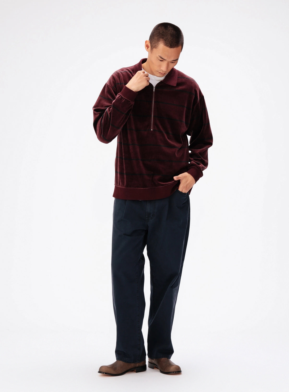 A man wearing a relaxed-fit burgundy quarter-zip BEAMS Striped Velvet Polo over a white collared undershirt, paired with dark trousers.