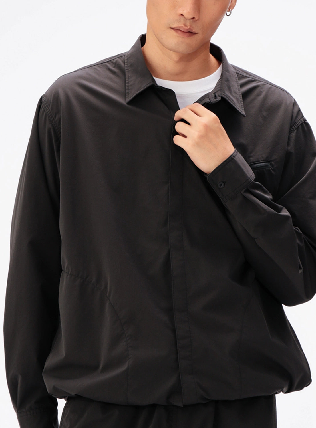 A person wearing a black BEAMS Tech Shirt over a white crew-neck t-shirt.