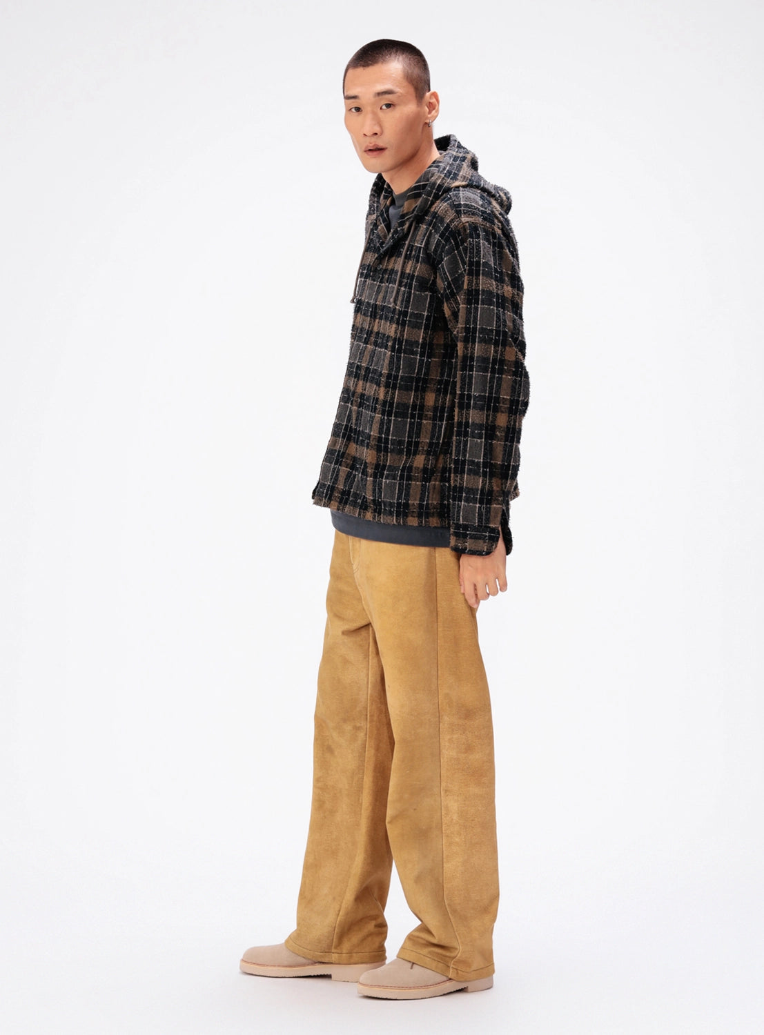A person wearing a brown and black BEAMS Bouclé Flannel Hooded Shirt over a dark shirt, paired with tan wide-leg trousers and light-colored shoes.