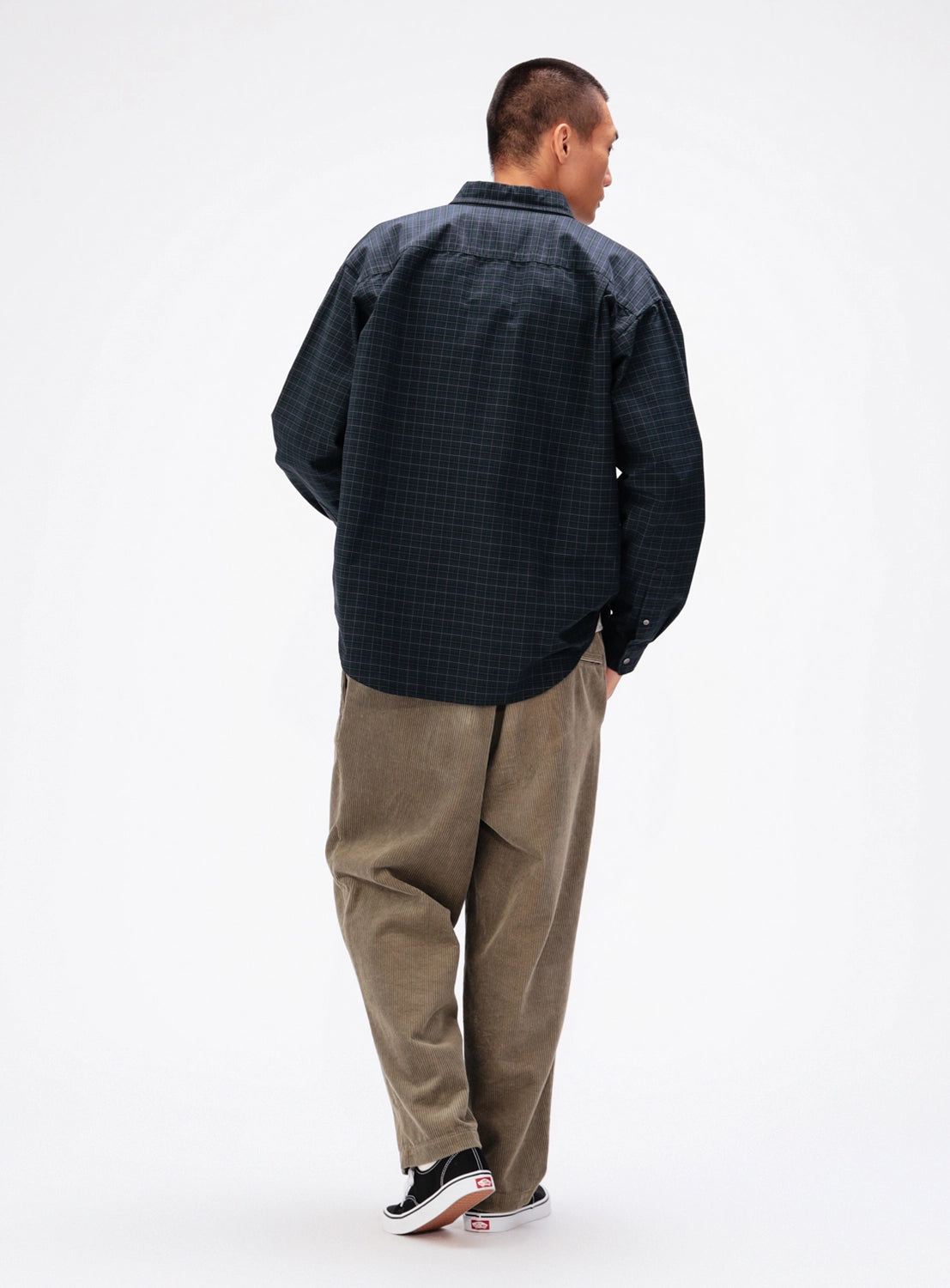 A person seen from behind wearing a BEAMS Heavy Oxford Button-Down Shirt in dark plaid, tan trousers, and black sneakers.