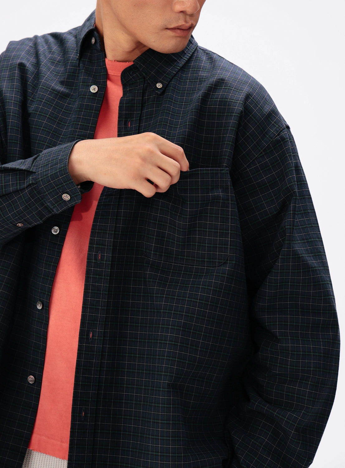 Person wearing a BEAMS Heavy Oxford Button-Down Shirt in a dark green and blue grid pattern over a coral-colored shirt.