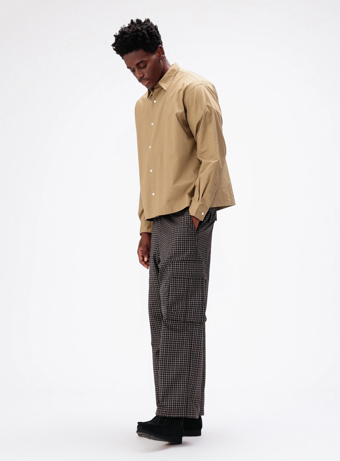 A person wearing a tan button-down shirt and BEAMS Pattern 6-Pocket Pants in a black and white checkered, relaxed-fit cargo style.
