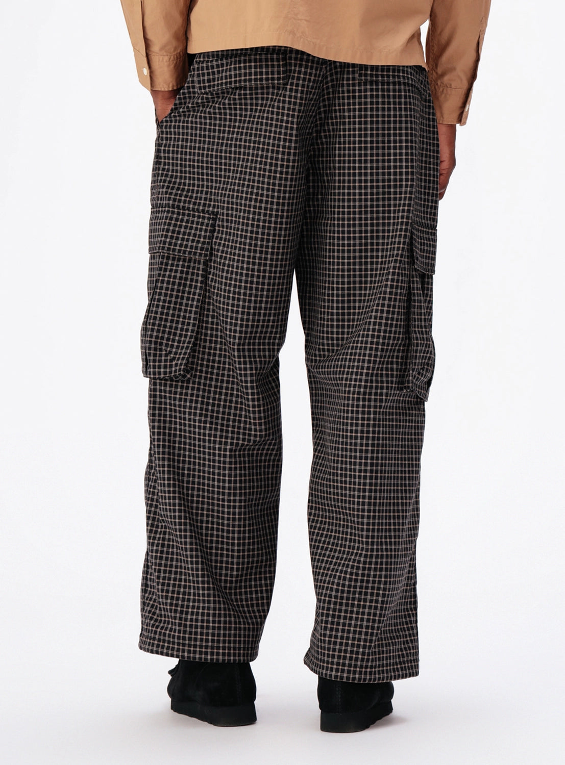 A person wearing BEAMS Pattern 6-Pocket Pants in a relaxed-fit, wide-leg, black and tan checkered pattern.