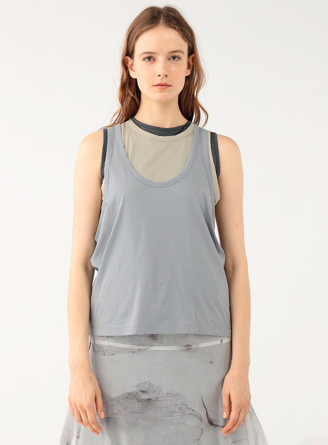 Woman wearing a gray layered sleeveless top.