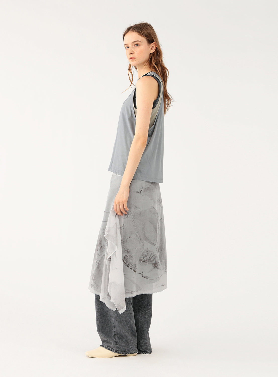 Side view of a woman wearing a gray layered sleeveless top.