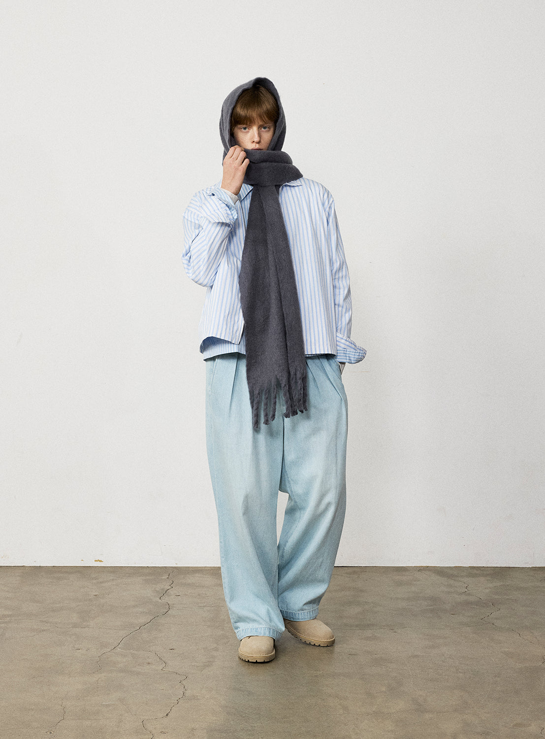 A person wearing a striped button-down shirt, light-wash Wide Denim Slacks by BEAMS, tan shoes, and a gray scarf wrapped around their head and neck.