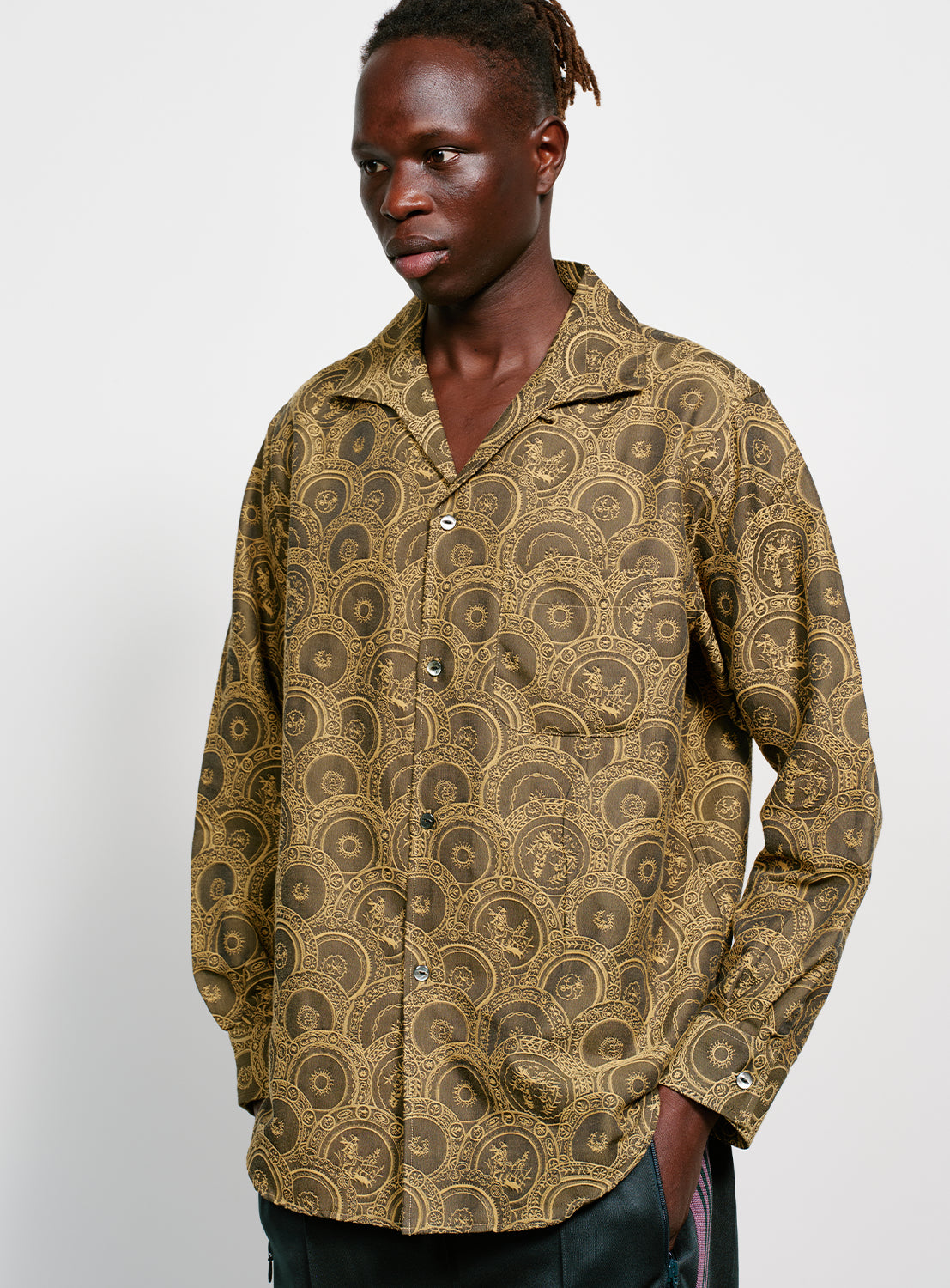 Model wearing a brown and yellow Italian patterned, collared button down shirt. 