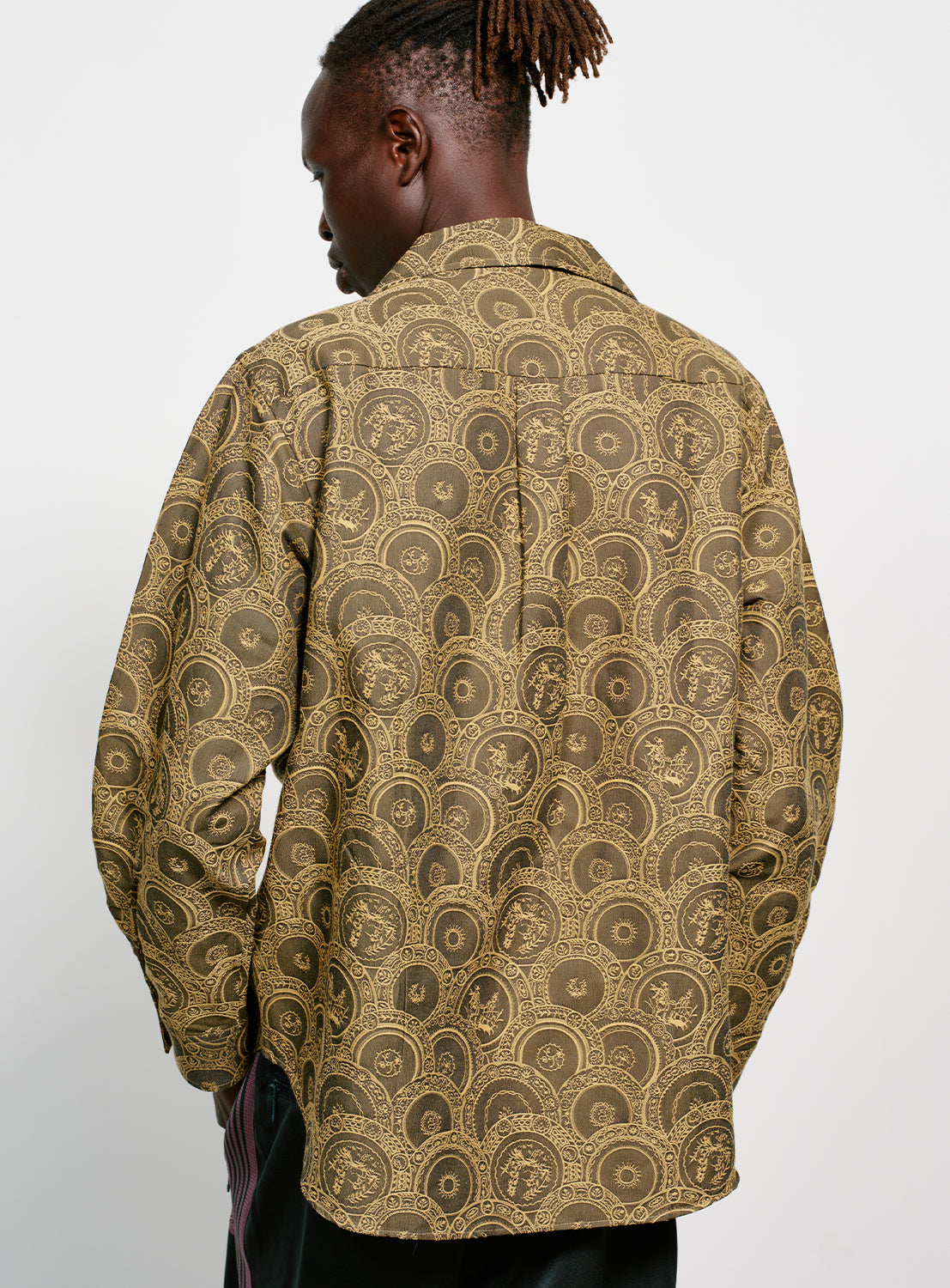 Backside of model wearing a brown and yellow Italian patterned, collared button down shirt. 