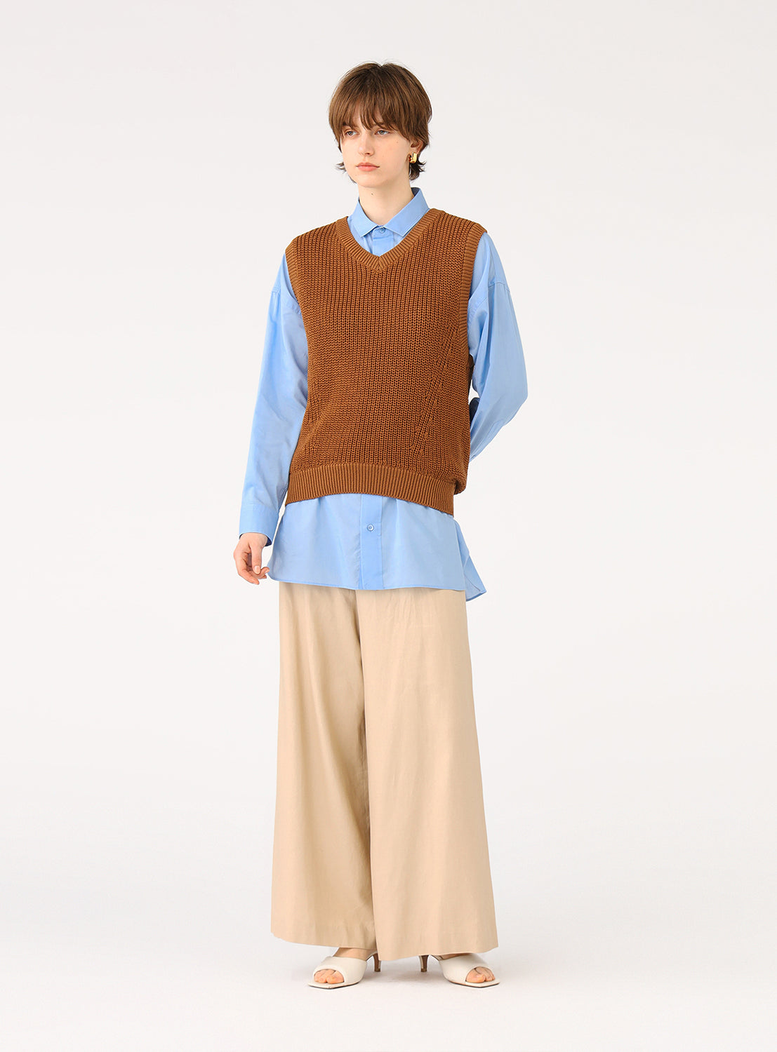 Model wearing the brown knit vest, showcasing the full outfit with a blue shirt and wide-leg pants.