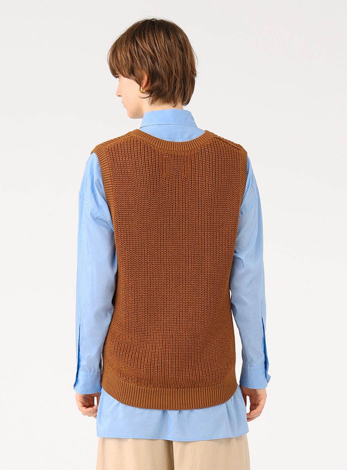 Back view of a model in the brown camel color knit vest, highlighting the layering over a blue shirt.
