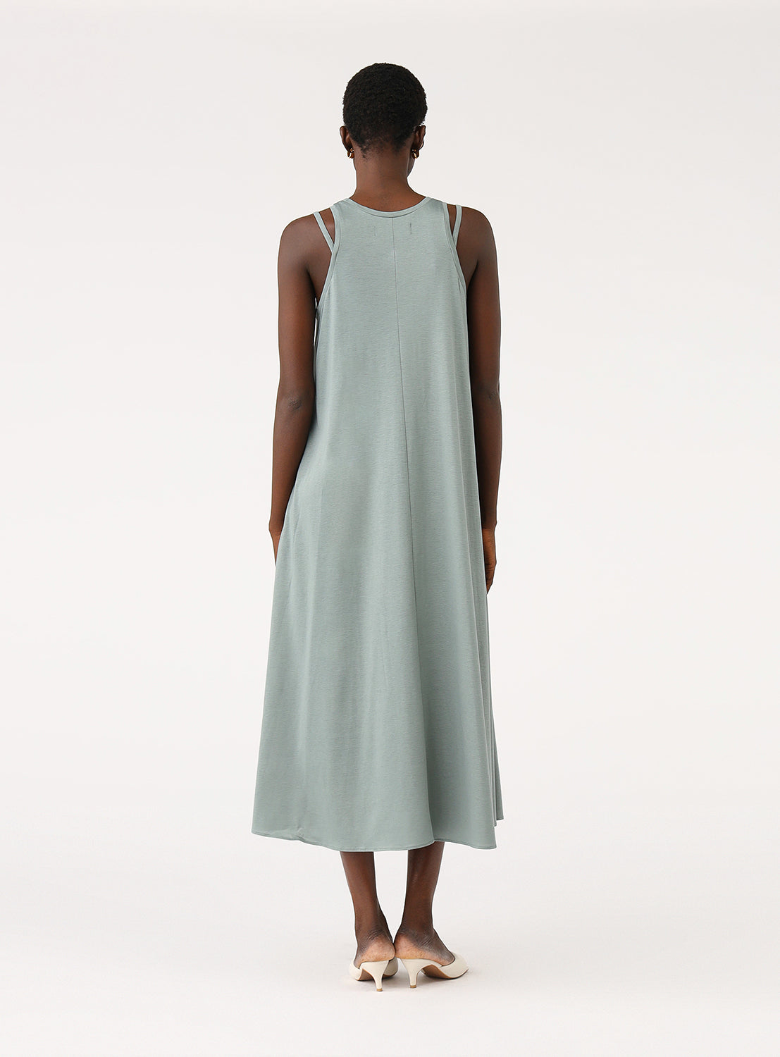 Back view of a model wearing a sage green A-line midi dress, highlighting the relaxed fit and crew neck.