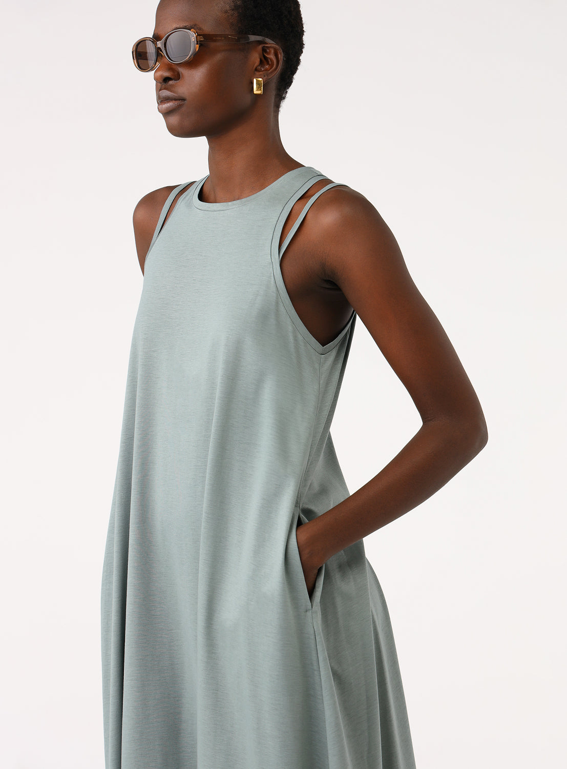 Close-up of a model wearing a sage green midi dress, showing the neckline and side pockets.