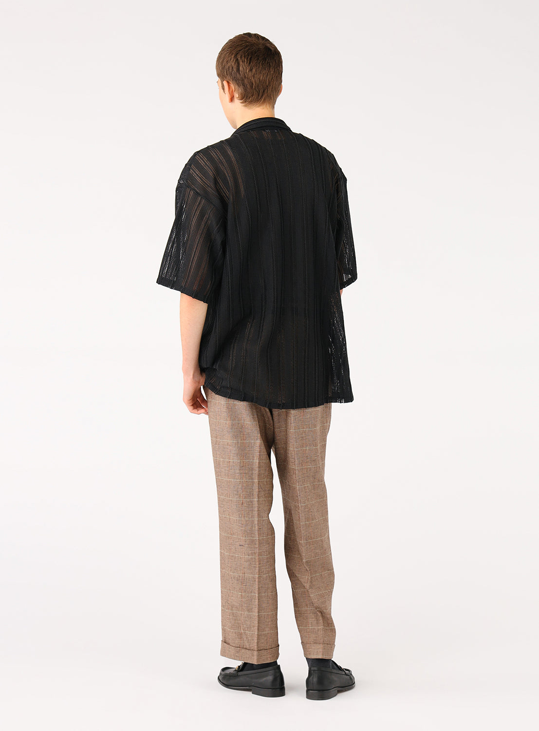 Back of a model wearing a black mesh shirt, highlighting its lightweight and breathable utilitarian design.